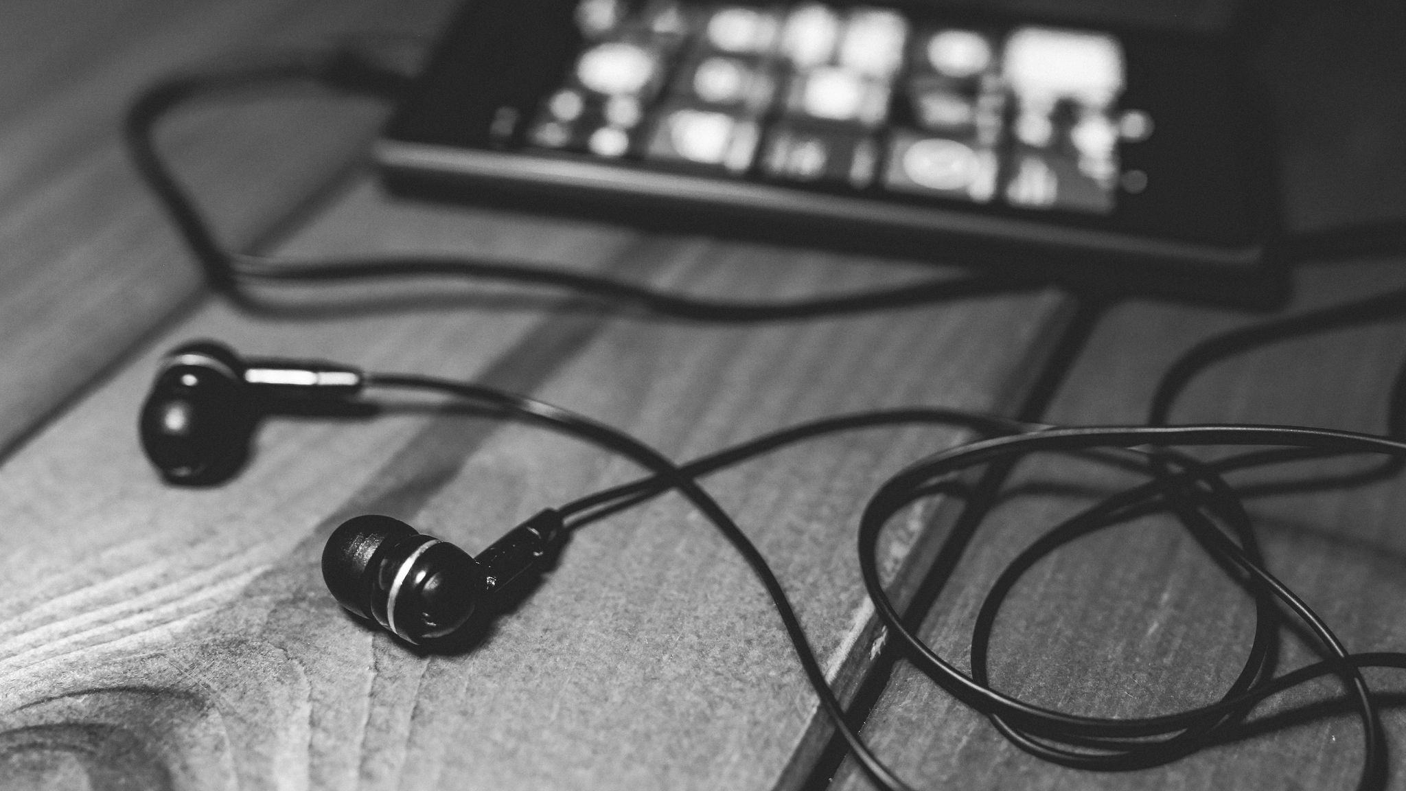 Black earbuds and smartphone on wooden table