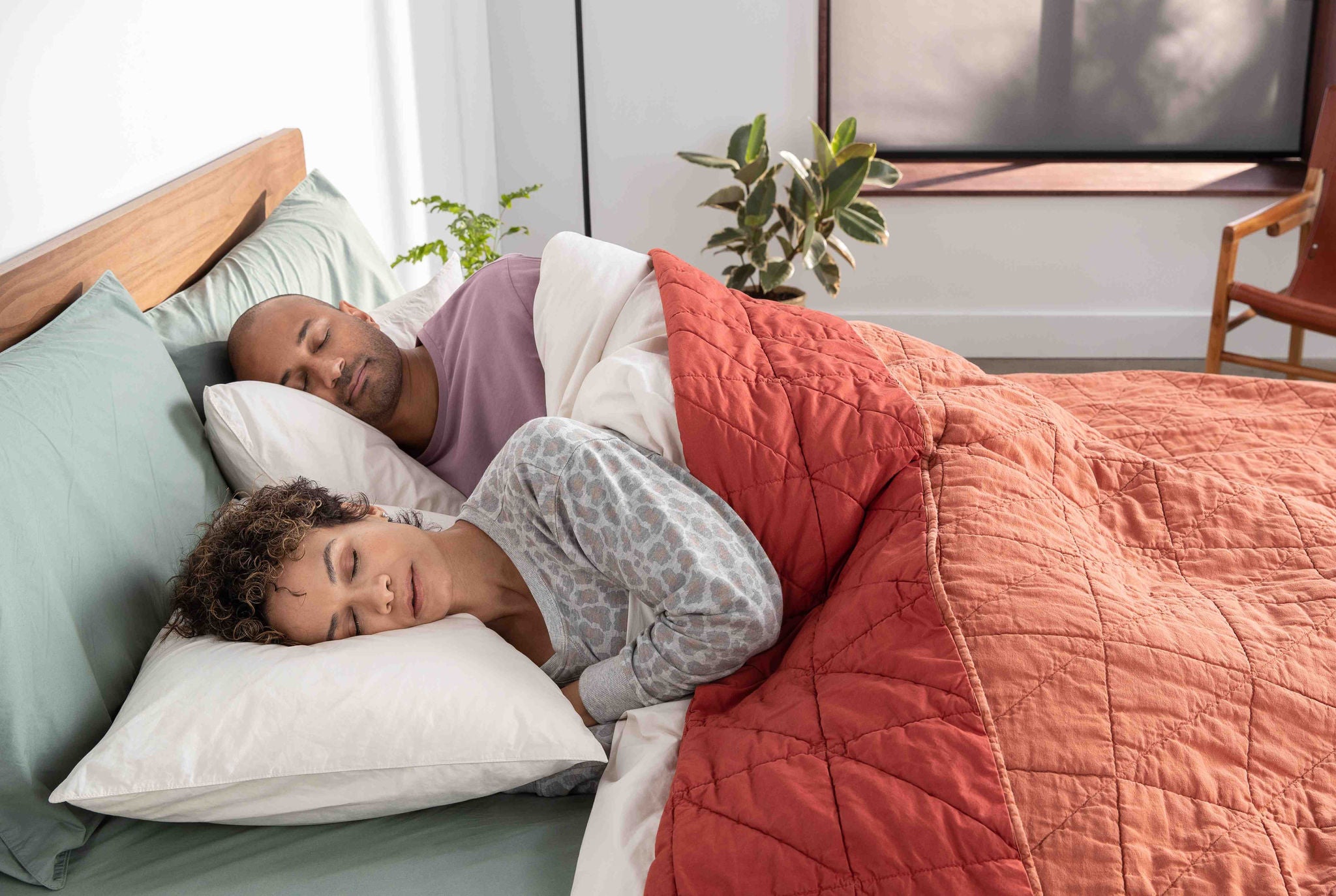 Couple sleeping under red quilt in bedroom