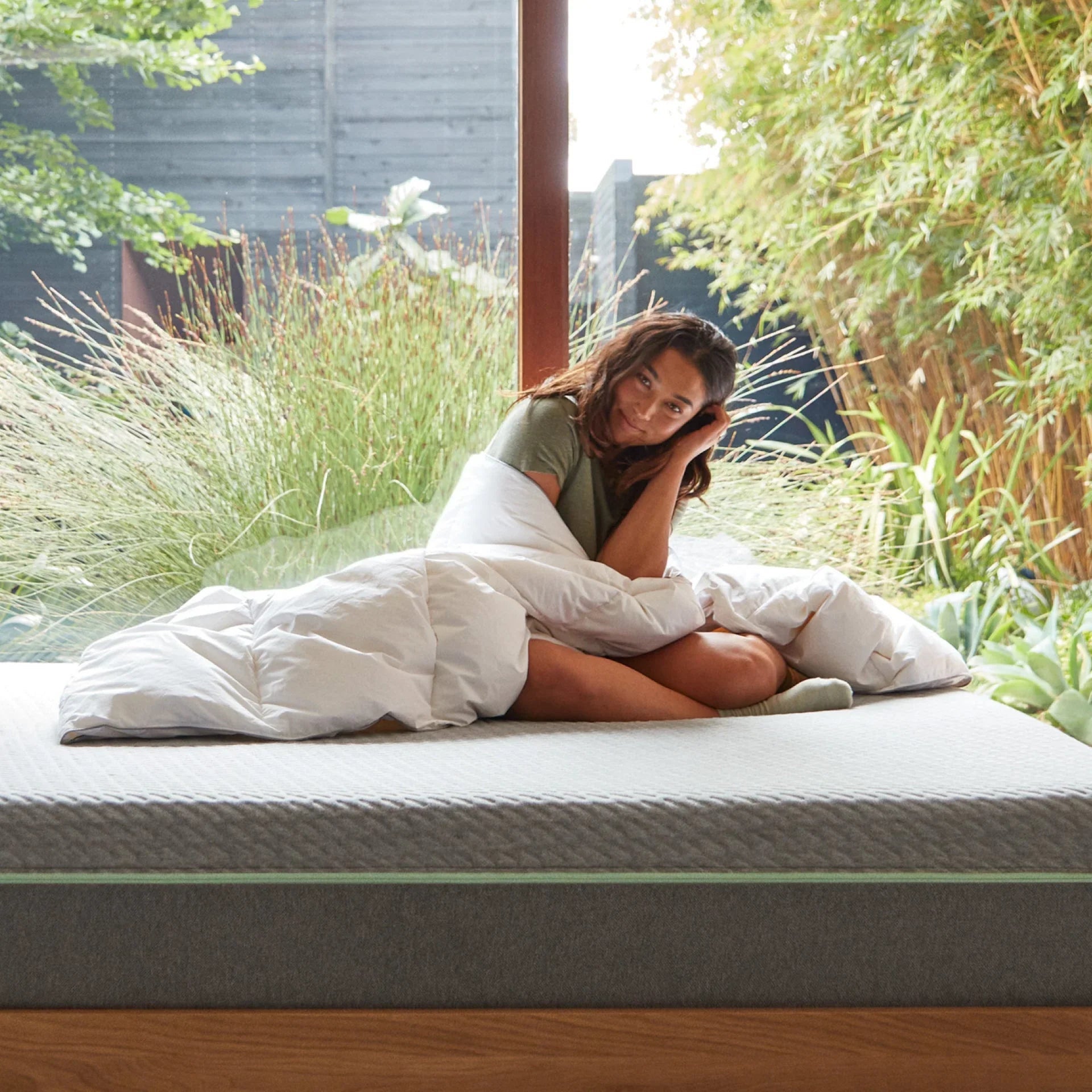 Woman sitting on modern mattress outdoors