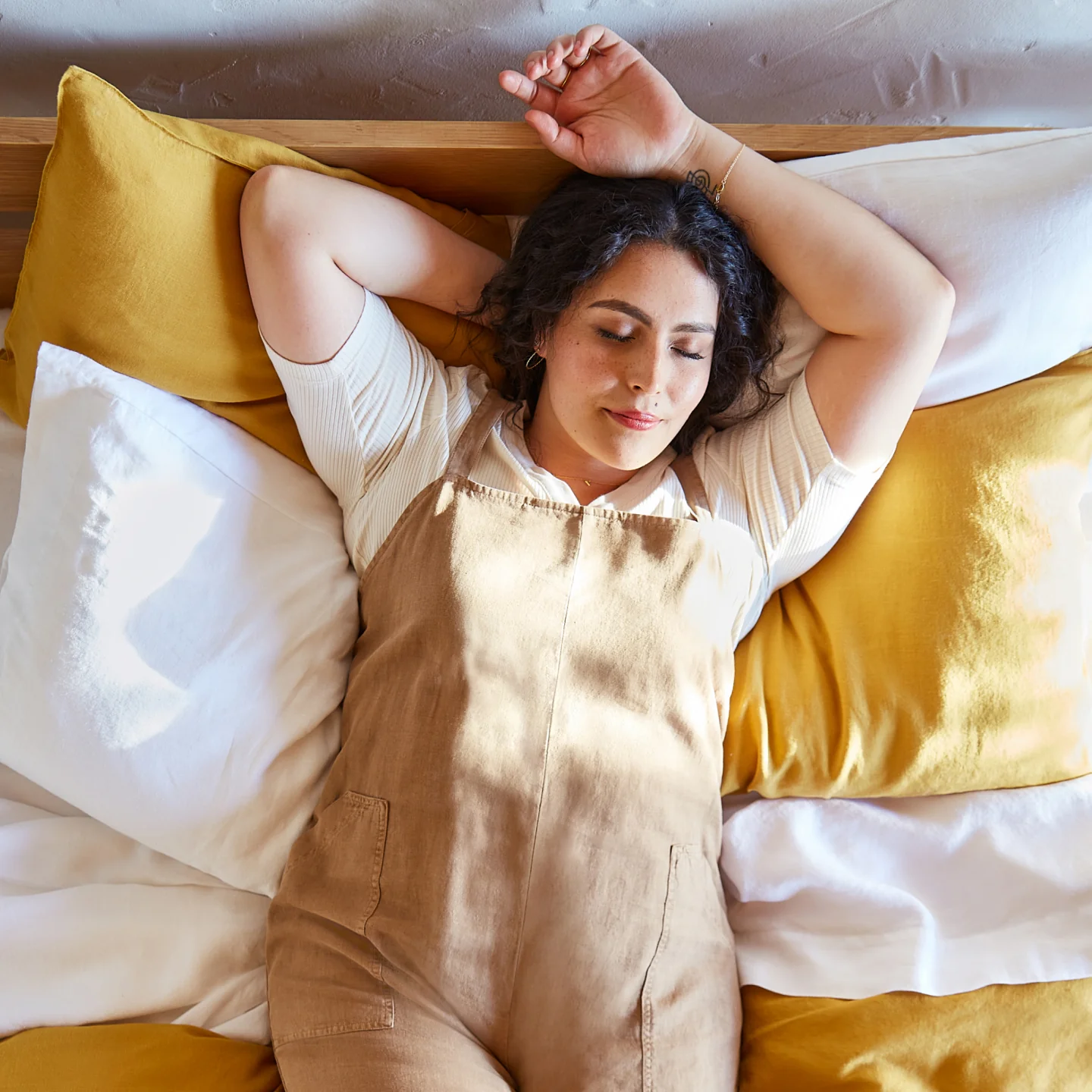woman laying on mustard sheets
