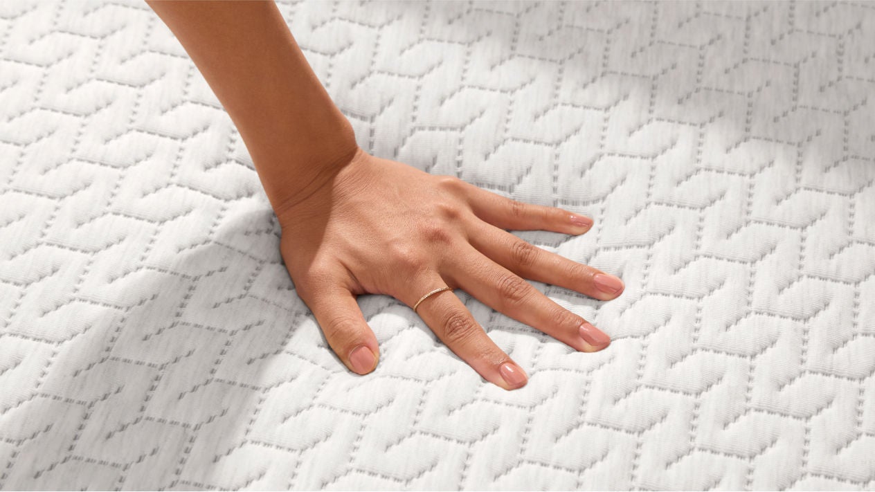 Hand pressing white textured mattress surface