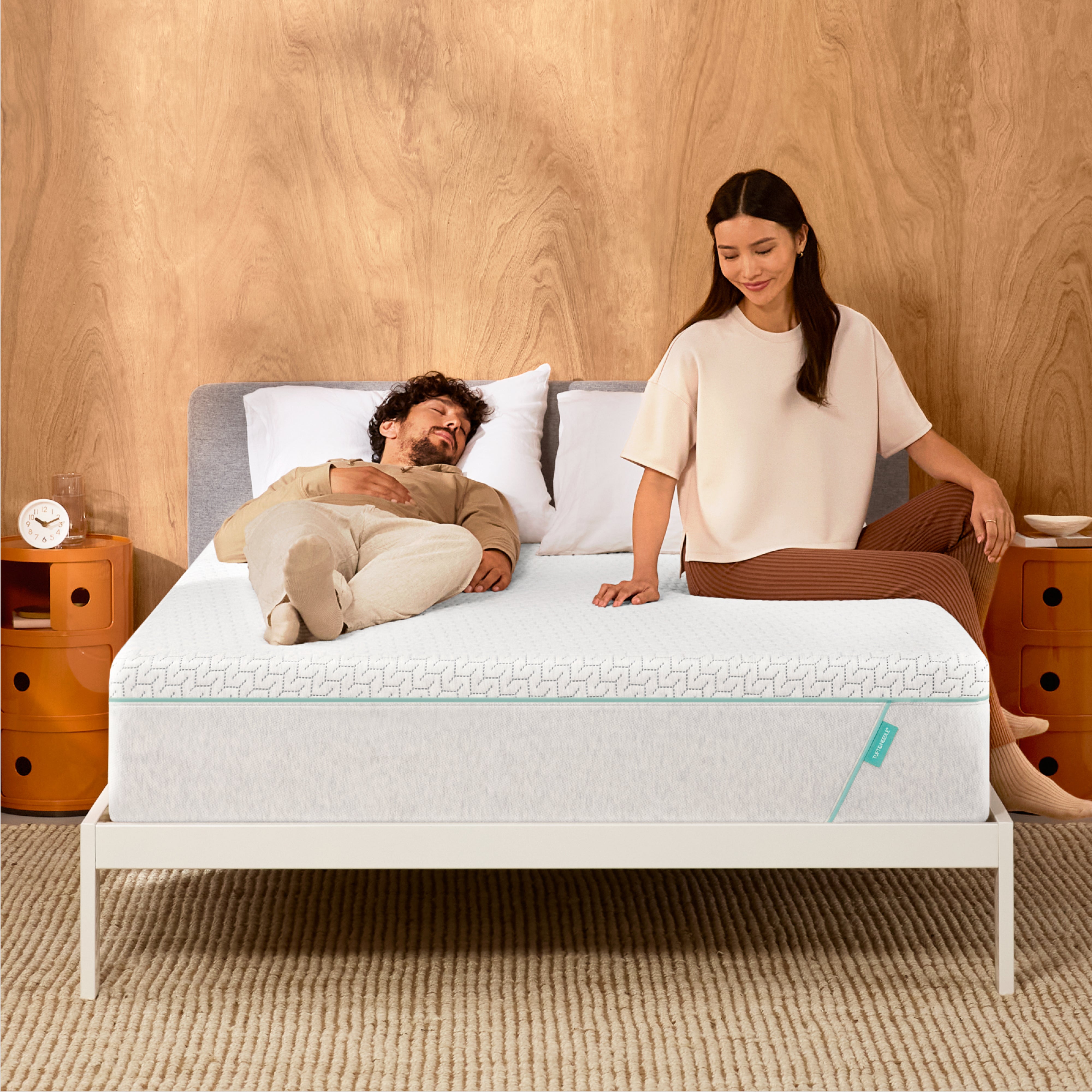 Man and woman laying on a Tuft & Needle Original Hybrid mattress sitting in a white bedframe