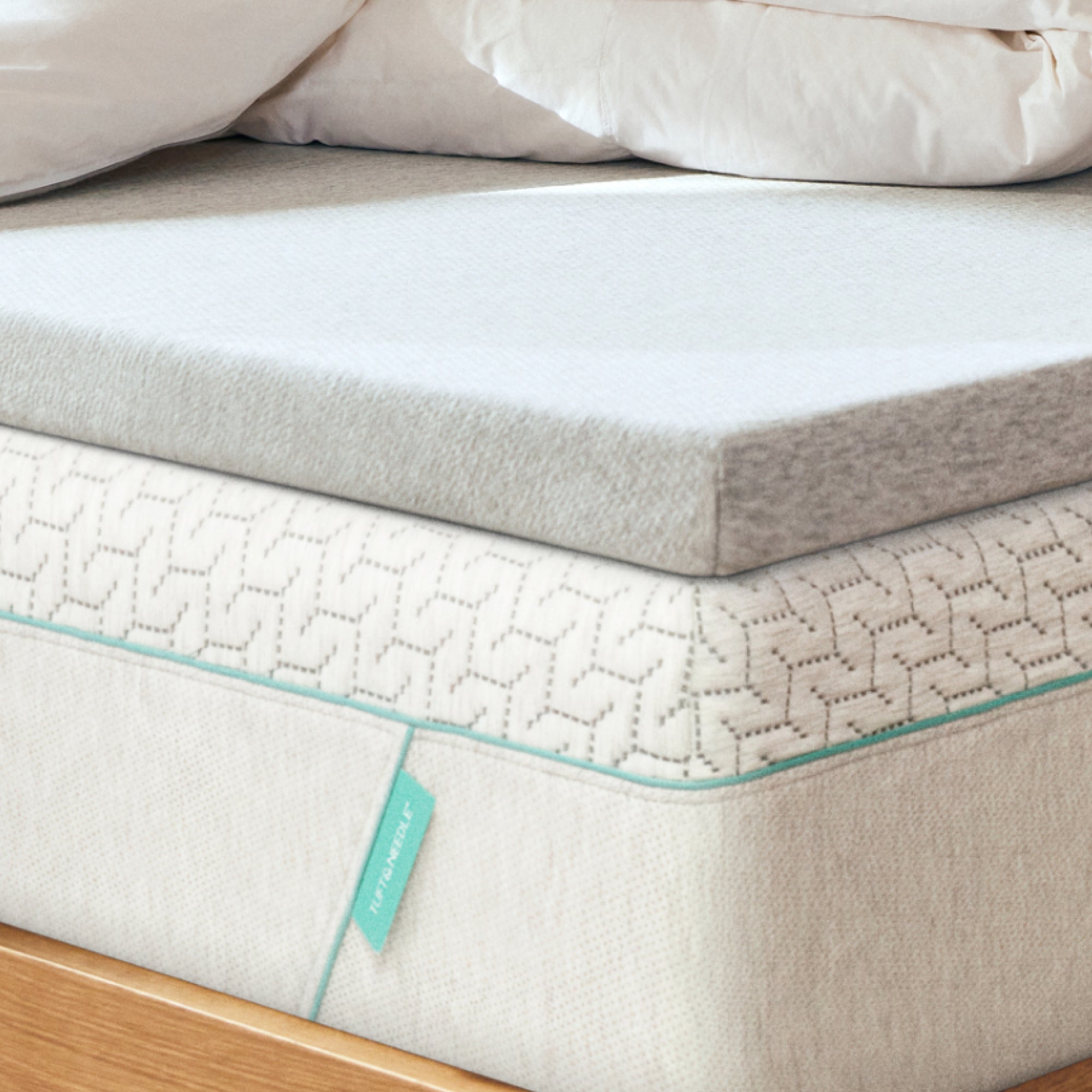 Tuft and Needle mattress topper on top of a Tuft and Needle Original mattress on wooden frame.